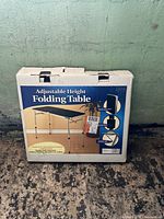 Image of original packaging box showing adjustable height folding table illustration and features.