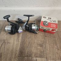 Three fishing reels placed side by side: two black and silver Shimano 2500FB reels and one new Single Action Fly Reel model 44 in original box.