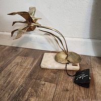 Side angle showing three brass geese in flight attached to marble base, with visible tag and signature.