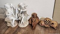 Full view of the four garden decor pieces: two white plaster fairies, one cement angel, one cast iron fish.