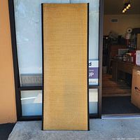 Full view of the tall rectangular tatami mat standing upright outside a building, showing overall size and shape.