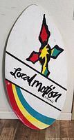 Front side of wooden skim board with colorful Local Motion logo featuring red, yellow, green, and blue stripes.
