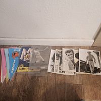 Photo showing a row of vintage sports pennants alongside several black and white signed photographs of actors and sports figures.