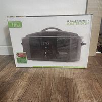 Photo of Tru 18 quart roaster oven in original box, showing front view with appliance image and branding.