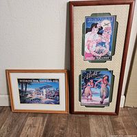 Three vintage airline advertisement pieces displayed on floor against wall; one bamboo framed single print and one double print in a textured frame