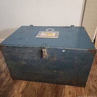 Front view of blue wooden storage chest with latch and slight wear