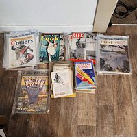 Wide view showing stacks and groups of vintage magazines, including Colliers, Life, Saturday Evening Post, Popular Mechanics