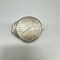 Front of the money clip showing the 1995 Liberty Silver Dollar with Olympic running event design featuring two runners near the finish line, Olympic rings, and text including 'LIBERTY', 'XXVI OLYMPIAD', 'IN GOD WE TRUST', and '1995'.