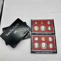 Two 1981 United States Proof Sets with black cardboard sleeves, each containing six proof coins in red holders.