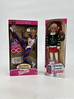 Two sealed Barbie dolls in original packaging: Olympic Gymnast Barbie and Holiday Season Barbie.