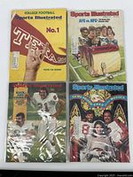 Four Sports Illustrated magazines shown on a flat surface, each in plastic sleeves. Covers visible: Texas college football No. 1 with yellow background; AFC vs. NFC with cartoon players on a couch; football kicker feature; Semi-Tough movie cover.
