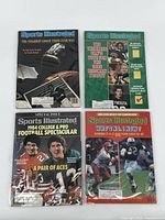 Four Sports Illustrated magazines from the 1980s, each in protective sleeve, front covers visible with football themes and players.