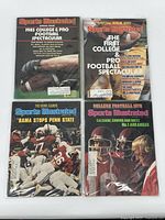 Four Sports Illustrated magazines with college and pro football themes inside protective sleeves, visible front covers showing different years and headlines.