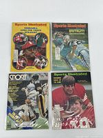 Four vintage Sports Illustrated magazines displayed in protective sleeves, showing front covers with various football themes and players.