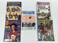 Five different Sports Illustrated sports magazines in clear protective sleeves laid out on a white surface.