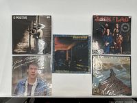 Five vinyl records arranged side by side showing album covers for each record.