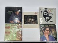 Five vinyl records in sleeves viewed from above showing cover art and labels.