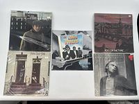 Five vinyl records displayed flat on white background, showing cover art and sleeves.
