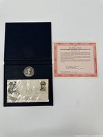 Full view of the commemorative set including the medallion in case, the certificate, and the first day cover envelope.