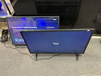 Two TVs standing on floor, one displaying Fire TV logo and the other showing Vizio network error screen.