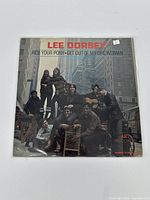 Front cover of the Lee Dorsey vinyl record Ride Your Pony showing the artist and group in city street setting.