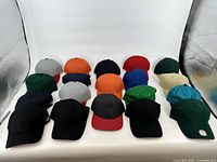 Photo showing 20 plain baseball caps in different colors arranged in rows.