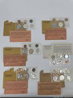 Overview of six sealed mint coin sets on white background (five Philadelphia proof sets and one San Francisco Special Mint Set).