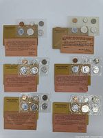 Six sealed proof sets arranged in two columns of three atop white background