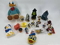 Overview of 21 vintage Disney and cartoon character toys including large Donald Duck plush and various small plastic figurines.