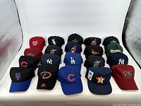 Photo showing 20 new baseball caps with tags, featuring logos from various MLB teams such as Washington Nationals, Chicago White Sox, Houston Astros, San Francisco Giants, New York Yankees, Detroit Tigers, Los Angeles Dodgers, Chicago Cubs, Arizona Diamondbacks, Philadelphia Phillies, Cleveland Guardians, Seattle Mariners, Atlanta Braves, New York Mets, Miami Marlins, San Diego Padres.