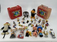 Wide shot showing the two Looney Tunes lunch boxes at the back and a collection of about 40 Looney Tunes character toys including hard figurines and plush in front.