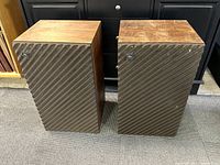 Front view of two vintage JBL L50 speakers side by side, showing wood veneer tops and brown ribbed fabric grille with JBL badges