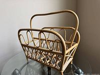 Front side angle view of vintage bamboo magazine stand on glass table.