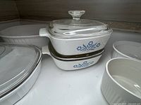 Photo showing stacked rectangular Corning Ware casseroles with blue cornflower pattern and glass lids.