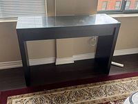 Front view of the rectangular dark wood couch table with glass top showing stickers and placement near window.