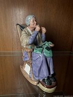 Side view of the Royal Doulton figurine showing the seated elderly woman in the rocking chair, holding sewing materials on her lap.