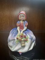 Front view of Royal Doulton Monica figurine showing detailed dress and floral basket.