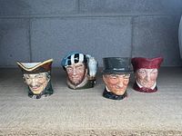 Four Royal Doulton miniature Toby mugs displayed side by side showing distinct hat styles and character faces.