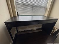 Full front view of the black two drawer desk showing drawer fronts and side panels.