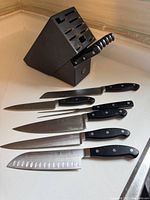 Knife set displayed with black knife block stand on countertop.