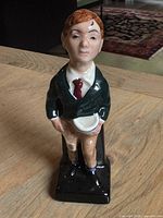 Full view of Royal Doulton Oliver Twist figurine standing on a wooden surface, showing the front details including clothing and base.