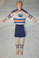 Front view of the Wayne Gretzky doll wearing Edmonton Oilers jersey and shorts, lying on a white background.