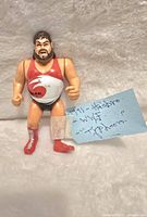Photo of 1991 Hasbro WWF/WWE Typhoon wrestling action figure against a white textured fabric background with a handwritten note.