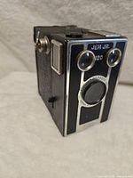 Front angled view showing Jem Jr. branding, twin viewfinder lenses, and single-element lens.