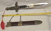 Full view of dagger with sheath and measuring tape showing length