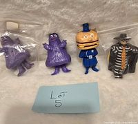 Four vintage McDonald's character figures including two Grimace figures, Officer Big Mac, and Hamburglar posed on a light-colored surface with a Lot 5 note.
