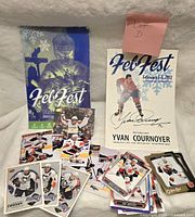 Full lot arranged on white fabric with visible Feb Fest program books, signed Yvan Cournoyer photo, and scattered hockey cards including Sidney Crosby cards.