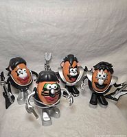 Four Mr. Potato Head figures styled as rock band members with silver and black costumes and accessories.