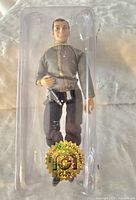 Photo of Mego Star Trek Captain Kirk figure in gray uniform with gold trim and black pants, inside original plastic bubble packaging. Figure has holographic gold seal.