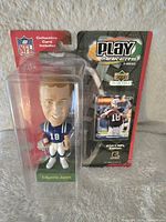 Front view of new sealed Peyton Manning bobblehead in Colts uniform with misprinted name 'Edgerrin James' on green base and collectible card included.